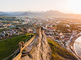 An old defensive fortress with towers in the city of Sudak in the Crimea at dawn from the height.