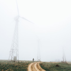 One man looks at huge wind farms, covered with fog, high in the mountains