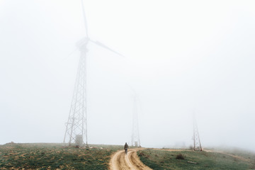 One man looks at huge wind farms, covered with fog, high in the mountains