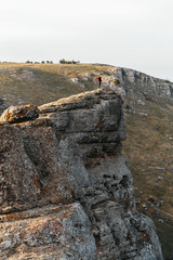 The guy stands on the edge of the cliff before the cliff at a huge height In the southern Demerdzhi in the Crimea