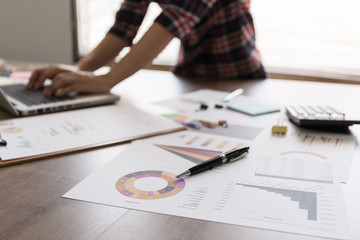 Pen on the background graph, blurred people working on the laptop.