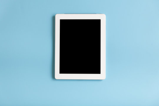 Top view of tablet on the blue pastel color background.
