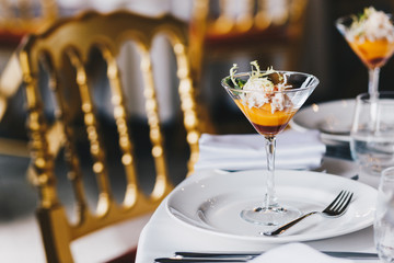 Indoor shot of nice served table with white plates, forks and cocktail for special occasion: wedding, birthday or party. Elegant dinner banquet table with exotic beverage ready for guests