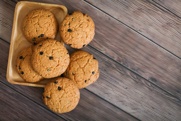 homemade oatmeal cookies folded in a pile on wooden plate and wooden background