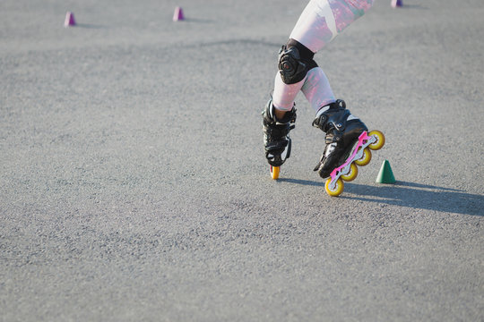 Cropped shot of teenager rollerblades on asphalt, has trial, wears rollerblade and protection on knees. Active lifestyle, leisure and hobby concept