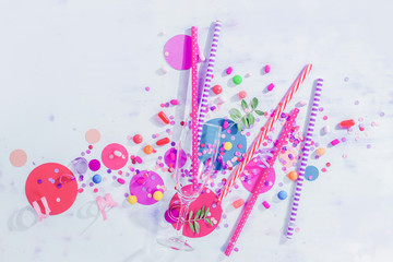 Champagne flute glass from above with straws, candies and confetti. Party concept with bar supplies, colorful flat lay with copy space