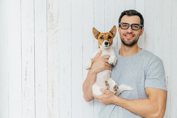 People, positiveness, animals and friendship concept. Happy unshaven male wears casual clothes,...