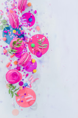 Macaroon cookies, confetti and candies in a colorful party supplies flat lay, dessert and catering concept on a light background with copy space