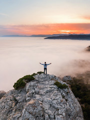 A man stands on the edge of a cliff above the dense fog that covered the sea, on Mount Kosmos in the Crimea