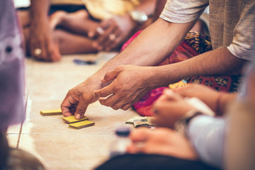 Group of balinese men playing cards sitting on the floor. Bali island.