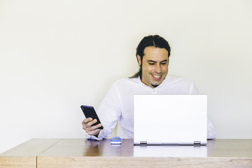 Modern designer checking mobile emails and laptop in urban office style workspace