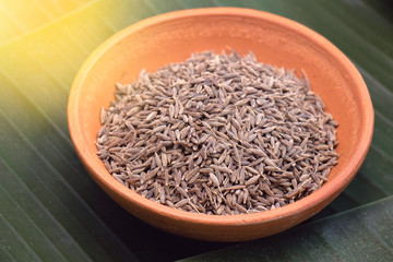 cumin seeds in pottery bowl on banana leaves background, an Indian spices in curry and mussaman curry