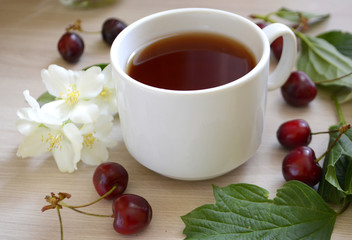 Cup of tea, cherry and flowers on the table