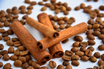 four cinnamon sticks surrounded by coffee beans