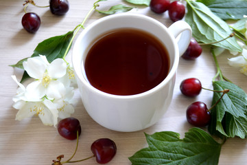Cup of tea, cherry and flowers on the table