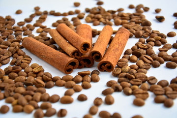 five cinnamon sticks surrounded by coffee beans