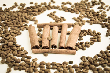 Five cinnamon sticks depict a cup of coffee next to the coffee beans on a light background