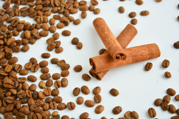 three cinnamon sticks next to coffee beans on a light background