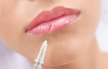 Young woman getting lip injection in beautician salon, closeup