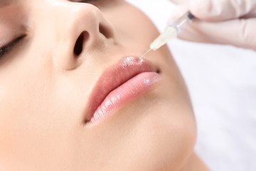 Young woman getting lip injection in beautician salon, closeup