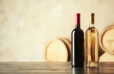 Fototapeta na wymiar Bottles of delicious wine and blurred barrels on background