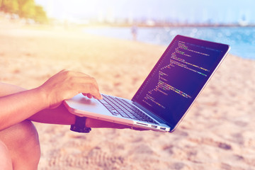 A programmer typing source codes at the beach on a sunny summer day. Studying, Working, Technology,...