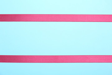 Simple pink ribbons on color background, top view