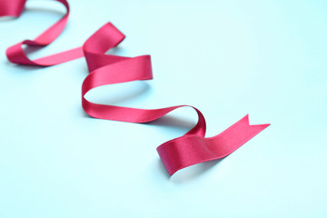 Simple pink ribbon on color background. Festive decoration