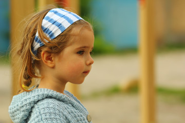 Close up profile portrait of a serious toddler girl in blue on playground