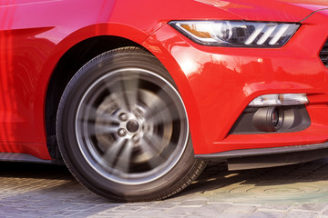 ..A fragment of a red sports car in motion.