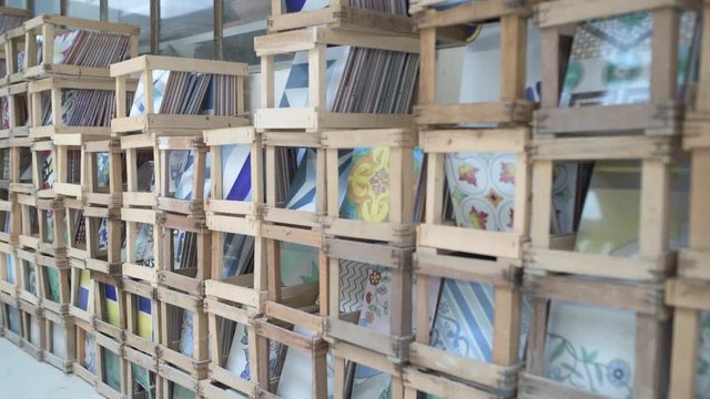 Open wood crates containing hand made and hand painted ceramic tiles in alternate focus