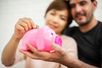 Couple putting coin into Pink Piggy Bank.