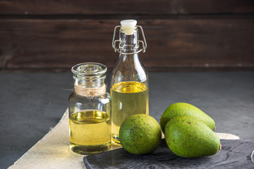 Avocado fruit and oil in glass bottle on dark background. Concept organic eco products for food and cosmetic procedures