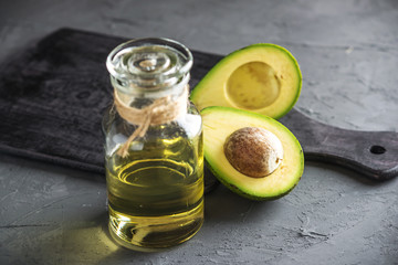 Avocado fruit and oil in glass bottle on dark background. Concept organic eco products for food and cosmetic procedures