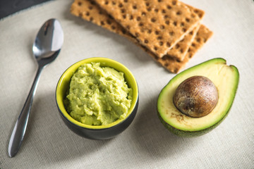 Cold appetizer of mashed avocado flesh with bread on the table. Traditional mexican food from organic eco products