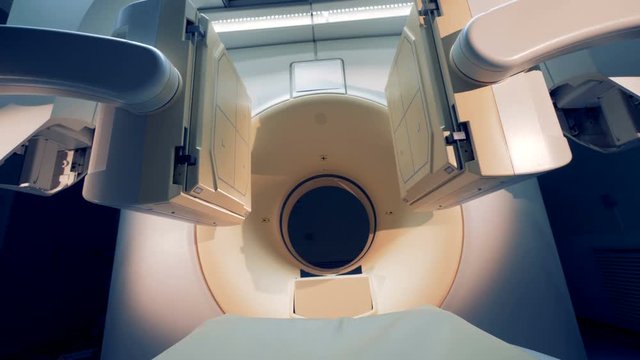Two tomographic scanning screens are moving closer and getting lowered. CT scanner in hospital with no patient.