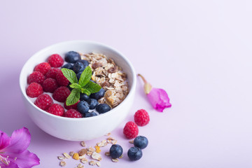 Smoothie bowl with yogurt, fresh berries and cereal on the pink background