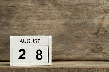 White block calendar present date 28 and month August on wood background