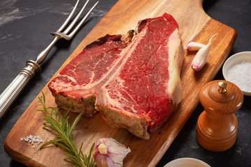 Meat for a barbecue. One raw piece of beef meat on the bone. steak t bone, salt, spices on a wooden...