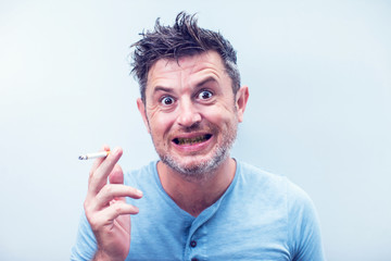 Handsome young man with brown hair wearing shirt isolated on grey background. Smoking cigarette. balack tooth