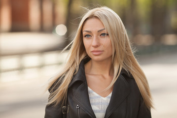 Portrait of the young beautiful smiling woman outdoors enjoying summer sun. Young woman outdoors portrait. Soft sunny colors. Beautiful blonde woman outdoor