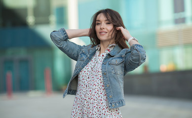 Young beautiful stylish girl walking and posing in short summer dress in city. Outdoor summer portrait of young woman