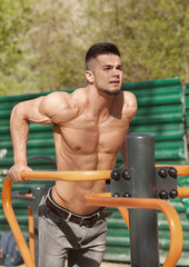 Young muscular man having training and doing exercise outdoors. Sport, fitness, street workout concept