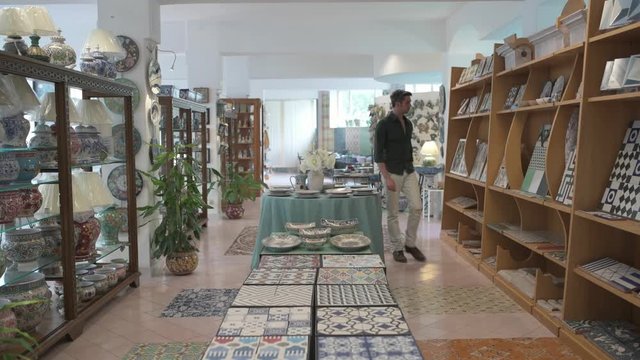 Young man walking in ceramic shop checking the quality of the goods