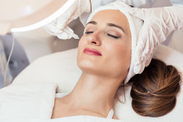 Beautiful woman relaxing during non-invasive facial treatment for rejuvenation in a contemporary beauty center with innovative equipment