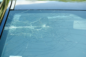 Broken and damaged front blue car windshield glass window in the crash accident with fatal outcome