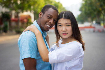 Portrait of happy young multiethnic couple hugging outdoors