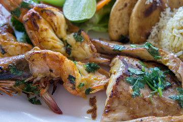 A variety of seafood grill close up macro. King prawns, crab langoustines and fish with torillas, cheese and lime.