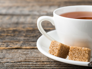 White tea Cup and saucer brown cane sugar on a rustic wooden background