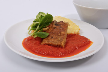 Tempeh with tomato sauce and dumplings on a white